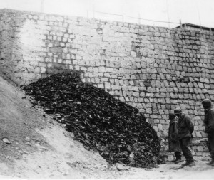 At Flossenburg, members of the 358th Infantry stare in shock at the seemingly endless pile of shoes, removed from dead prisoners before their bodies were burned - April 1945. (U.S. Army Signal Corps Photo, Courtesy National Archives)